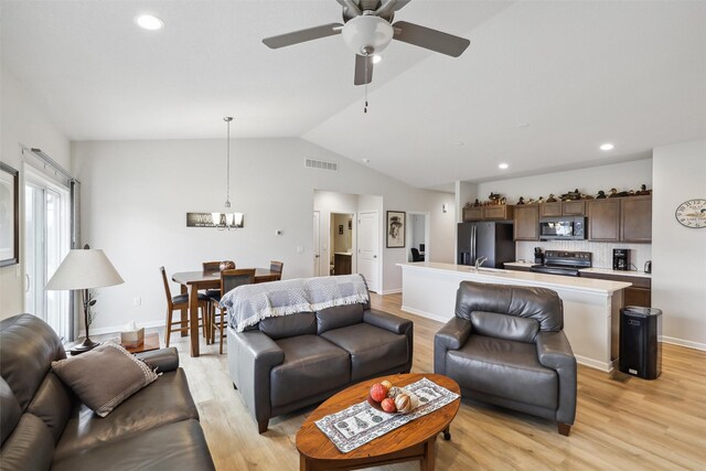 living room with light hardwood / wood-style flooring, ceiling fan with notable chandelier, and lofted ceiling