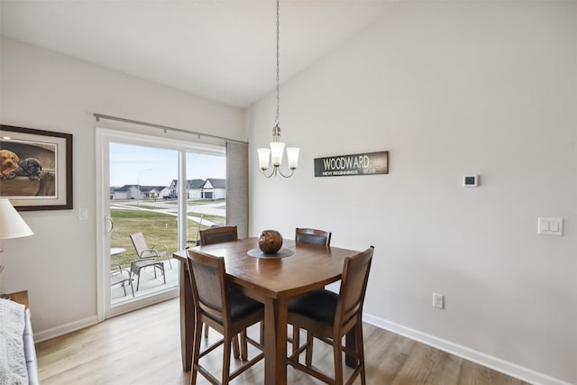 dining space with hardwood / wood-style floors, a chandelier, and vaulted ceiling