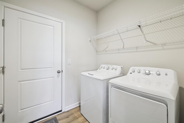 clothes washing area featuring washing machine and dryer and light wood-type flooring