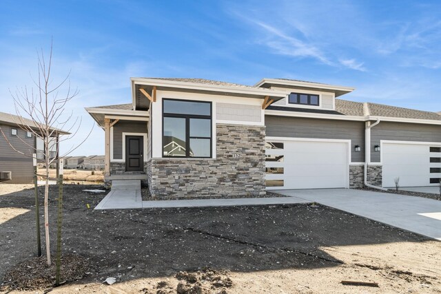 prairie-style home with stone siding and driveway