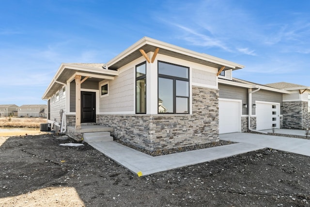 view of front facade featuring a garage, stone siding, central AC, and driveway