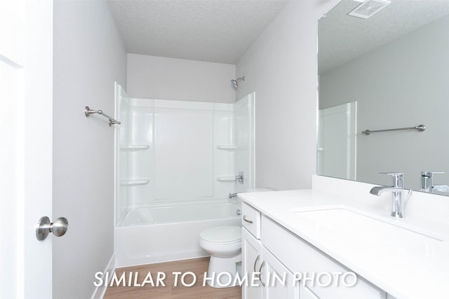 full bathroom featuring shower / bathing tub combination, vanity, hardwood / wood-style flooring, toilet, and a textured ceiling