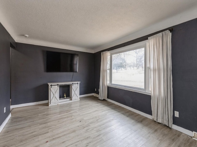 unfurnished living room featuring a textured ceiling and light wood-type flooring