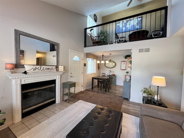 living room with plenty of natural light, a towering ceiling, a textured ceiling, and light hardwood / wood-style flooring