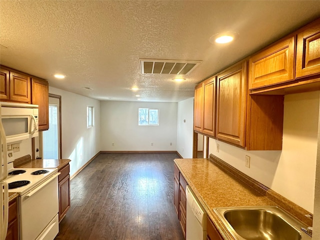 kitchen with a textured ceiling, sink, dark wood-type flooring, and white appliances