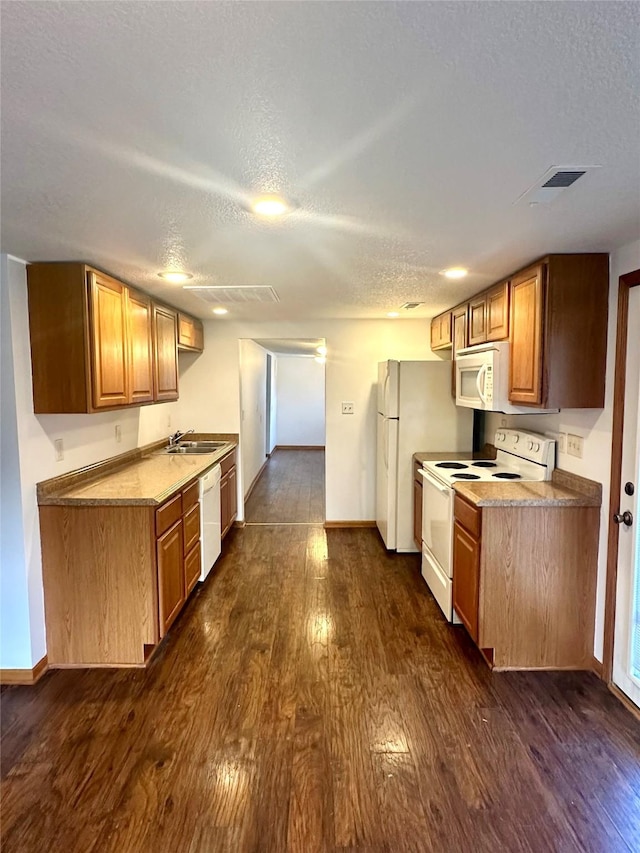 kitchen with a textured ceiling, white appliances, dark wood-type flooring, and sink