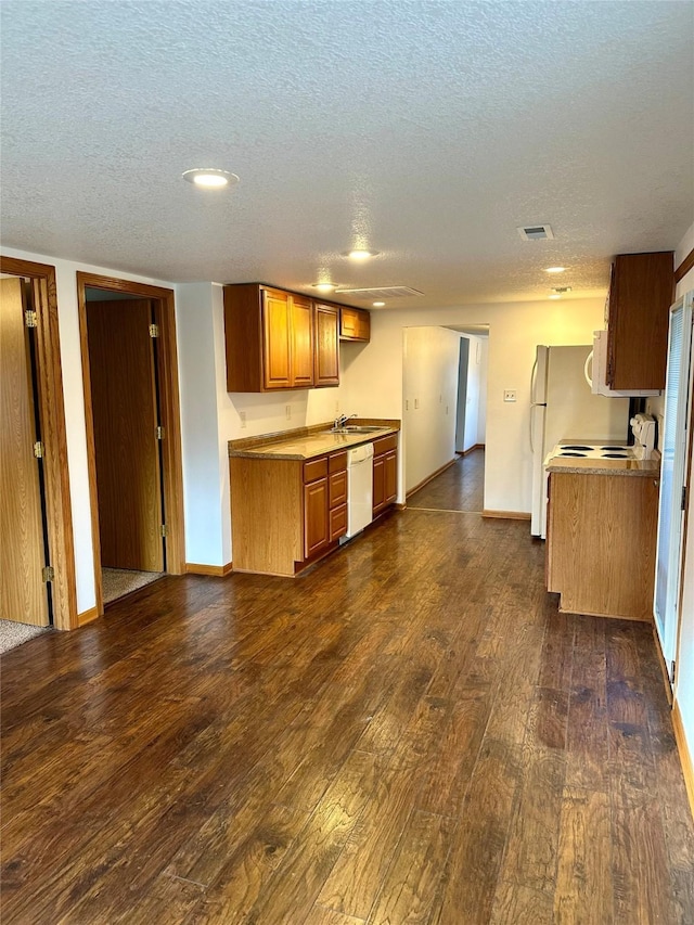 kitchen featuring a textured ceiling, sink, dark wood-type flooring, and white appliances