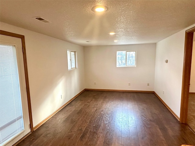 empty room with dark hardwood / wood-style flooring and a textured ceiling