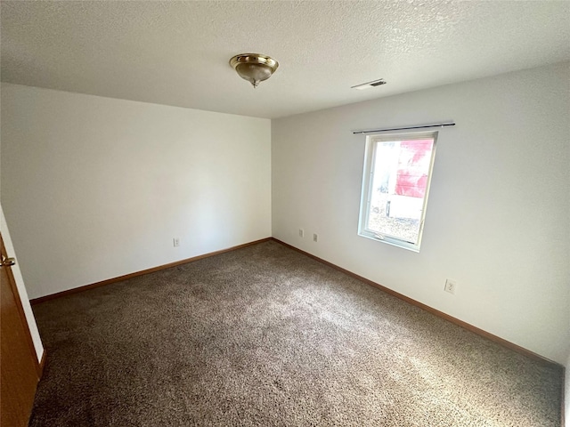 empty room with dark carpet and a textured ceiling