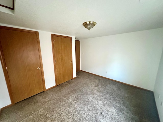 unfurnished bedroom featuring carpet flooring and multiple closets