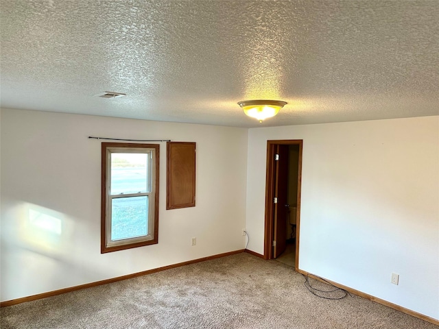 unfurnished room with carpet and a textured ceiling