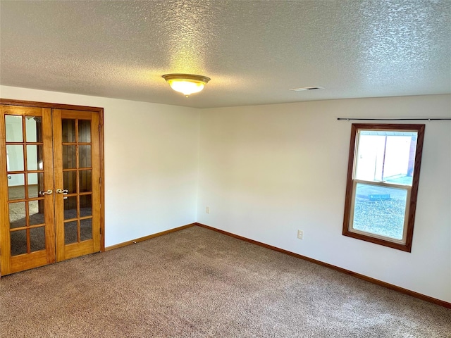 carpeted spare room featuring french doors and a textured ceiling