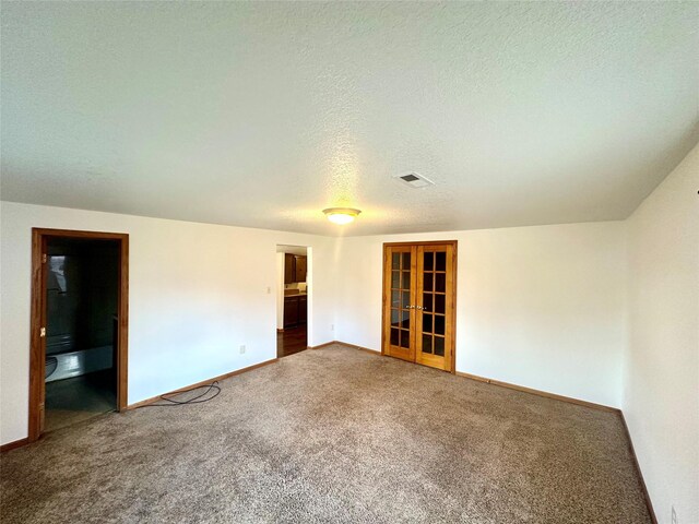 empty room with french doors, a textured ceiling, and carpet floors