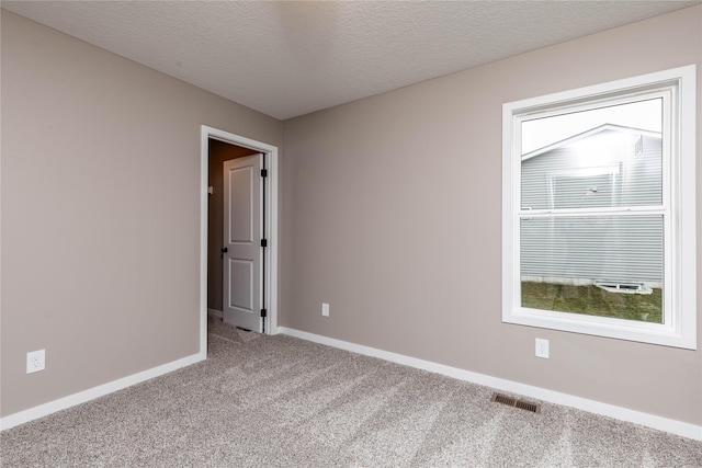 carpeted empty room featuring a textured ceiling