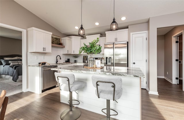 kitchen with tasteful backsplash, white cabinets, a kitchen island, and appliances with stainless steel finishes