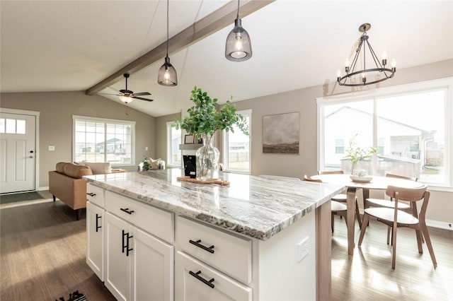 kitchen with ceiling fan with notable chandelier, wood-type flooring, lofted ceiling with beams, white cabinets, and hanging light fixtures