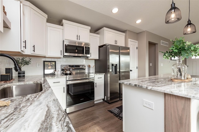 kitchen featuring sink, decorative light fixtures, dark hardwood / wood-style flooring, white cabinetry, and stainless steel appliances