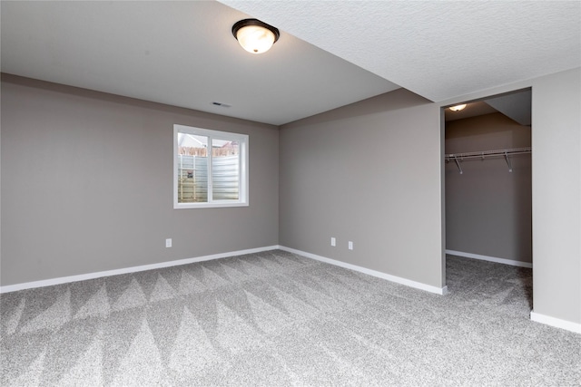 unfurnished bedroom with carpet flooring, a spacious closet, a textured ceiling, and a closet