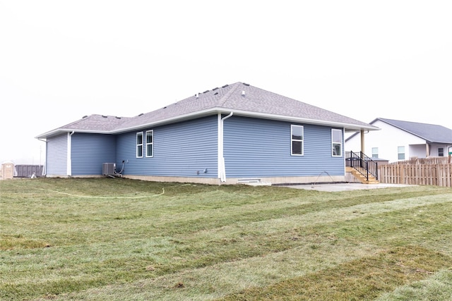 back of house featuring central air condition unit and a lawn