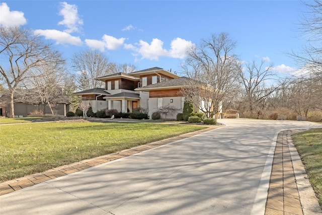 prairie-style house featuring an attached garage, concrete driveway, and a front yard