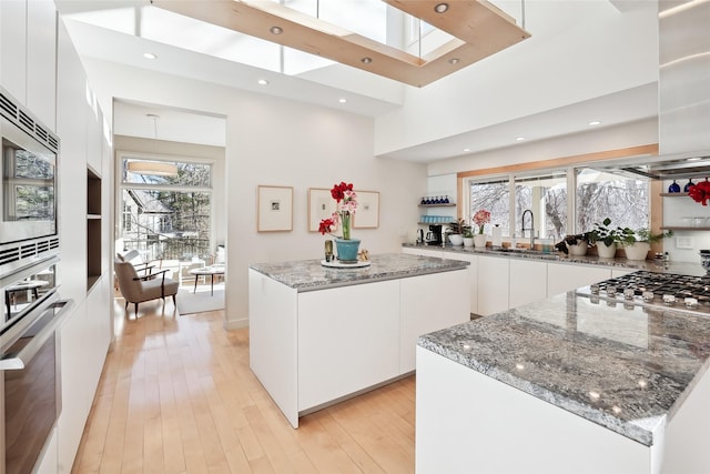 kitchen with modern cabinets, appliances with stainless steel finishes, white cabinets, and a center island