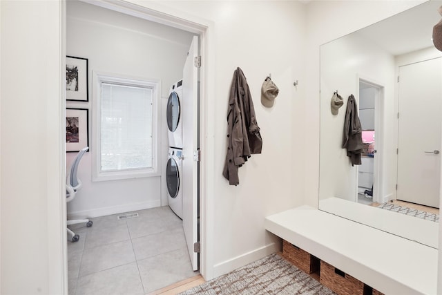 laundry room featuring laundry area, light tile patterned floors, baseboards, and stacked washer / drying machine