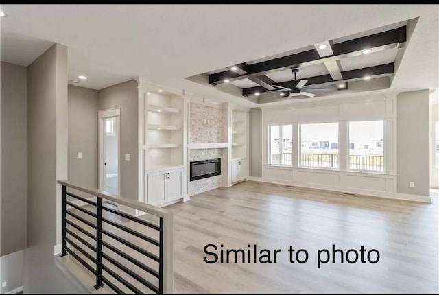 unfurnished living room featuring built in shelves, light hardwood / wood-style floors, ceiling fan, and coffered ceiling