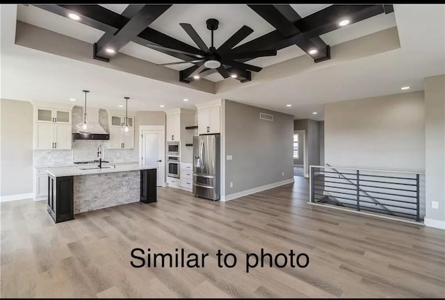 kitchen featuring stainless steel appliances, pendant lighting, a center island with sink, white cabinets, and light wood-type flooring