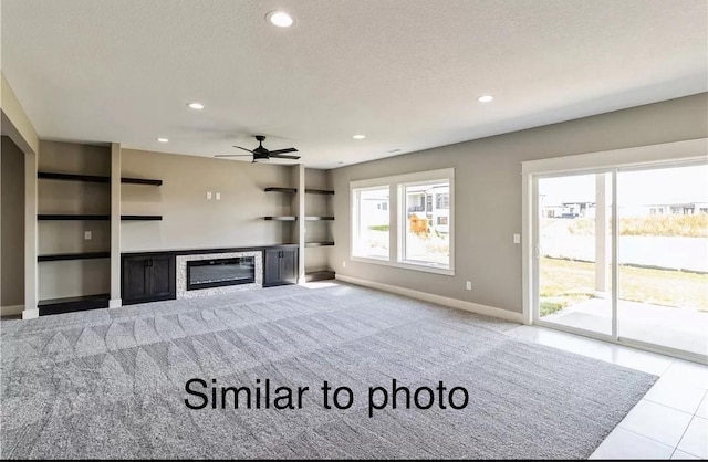 unfurnished living room featuring ceiling fan, light tile patterned flooring, and a textured ceiling