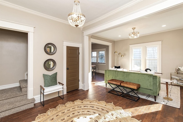 living room featuring a healthy amount of sunlight, crown molding, dark wood-type flooring, and an inviting chandelier