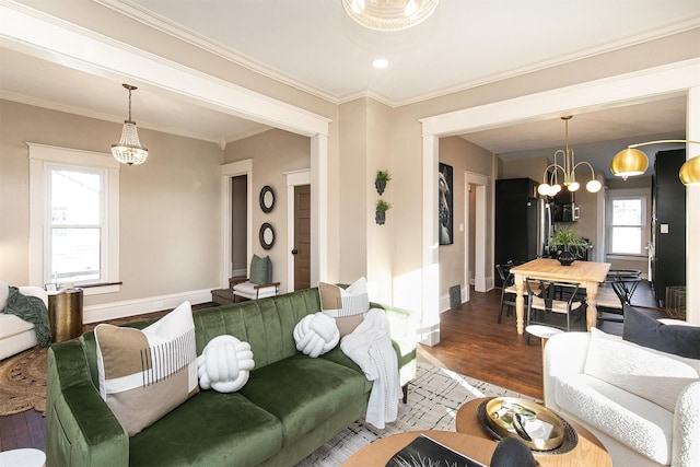 living room with hardwood / wood-style flooring, ornamental molding, and a notable chandelier