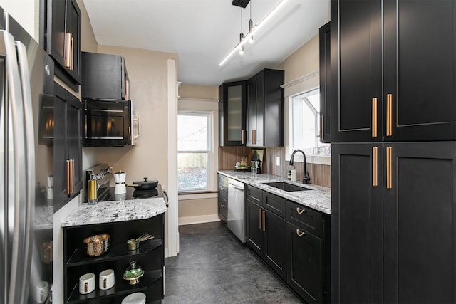 kitchen with light stone countertops, sink, decorative light fixtures, and appliances with stainless steel finishes