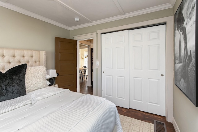 bedroom with dark hardwood / wood-style flooring, crown molding, and a closet