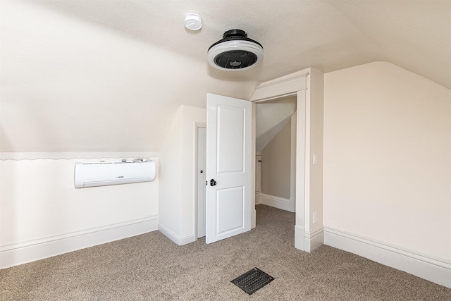 bonus room with a wall unit AC, a textured ceiling, light colored carpet, and vaulted ceiling