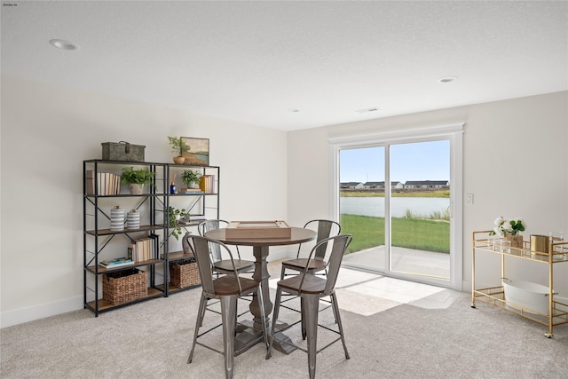 carpeted dining area with a water view