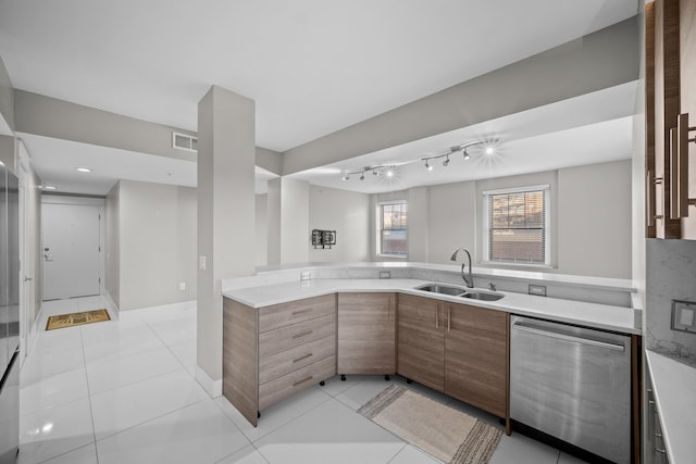 kitchen featuring stainless steel dishwasher, kitchen peninsula, light tile patterned floors, and sink