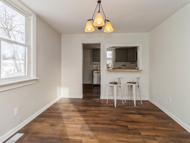 unfurnished dining area with a chandelier, dark hardwood / wood-style floors, and sink