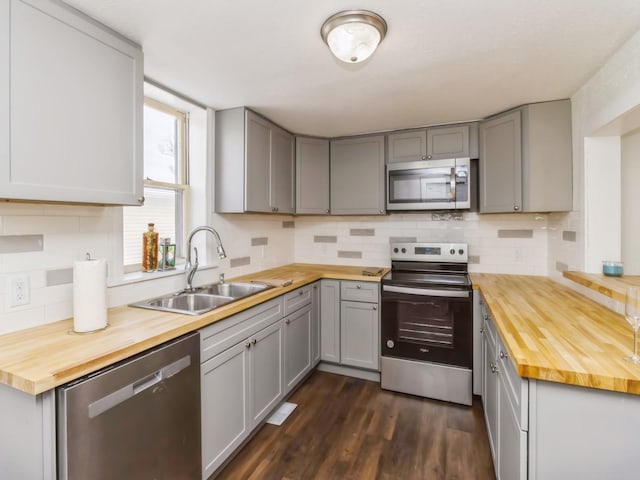 kitchen with dark wood-type flooring, sink, gray cabinets, butcher block counters, and stainless steel appliances