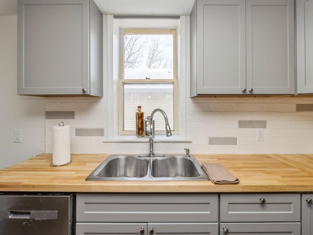 kitchen with dishwasher, wood counters, sink, gray cabinets, and tasteful backsplash