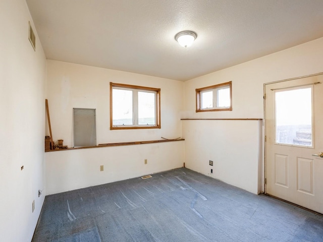 unfurnished room with dark colored carpet and a textured ceiling