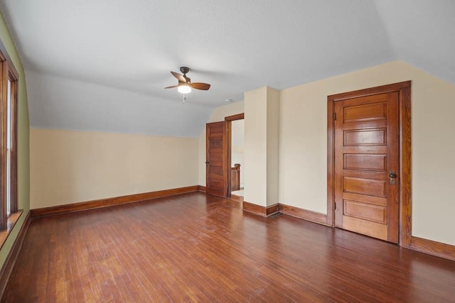 empty room with ceiling fan, dark hardwood / wood-style floors, and vaulted ceiling