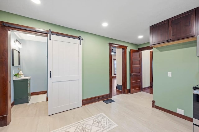 interior space with dark brown cabinetry, light hardwood / wood-style flooring, and a barn door