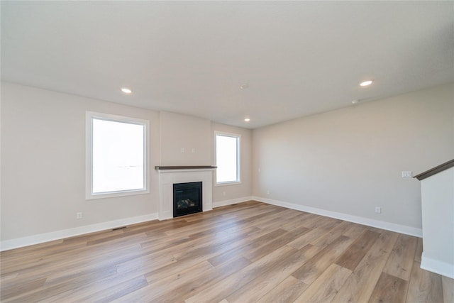 unfurnished living room with light wood finished floors, recessed lighting, a fireplace, and baseboards