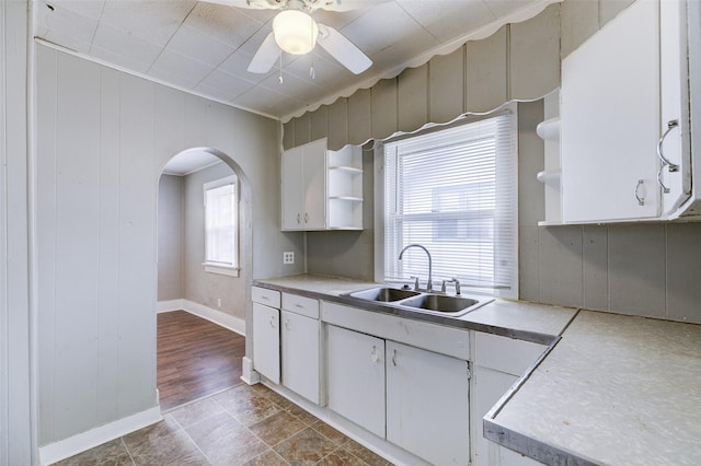 kitchen with plenty of natural light, wood walls, white cabinetry, and sink