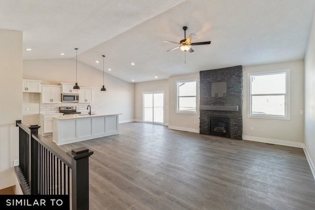 unfurnished living room with ceiling fan, dark hardwood / wood-style floors, a textured ceiling, lofted ceiling, and a fireplace