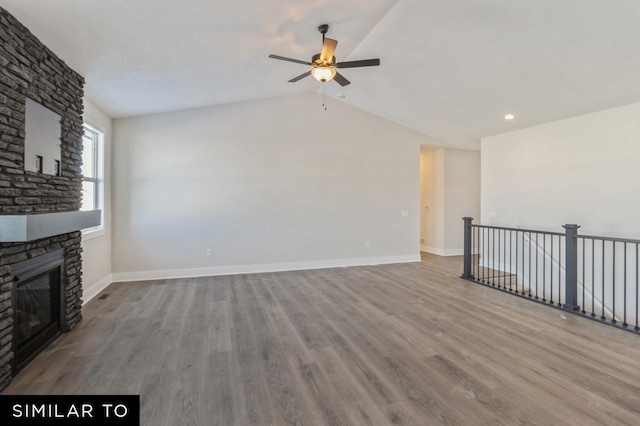 unfurnished living room featuring a stone fireplace, ceiling fan, hardwood / wood-style floors, and lofted ceiling