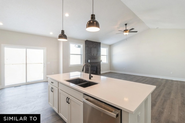 kitchen featuring stainless steel dishwasher, vaulted ceiling, a kitchen island with sink, sink, and decorative light fixtures