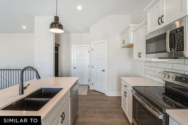 kitchen featuring white cabinetry, sink, stainless steel appliances, dark hardwood / wood-style flooring, and decorative light fixtures