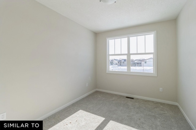 carpeted empty room with a textured ceiling