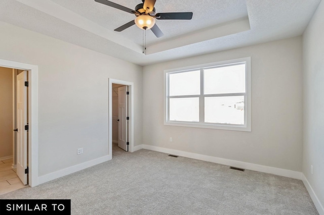 carpeted spare room with a tray ceiling, ceiling fan, and a textured ceiling